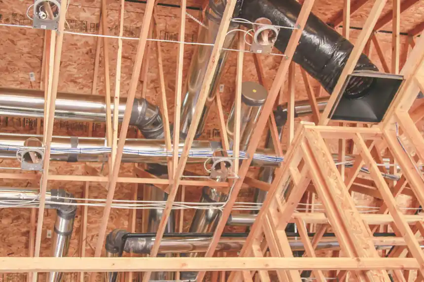 Duct runs through the roof trusses of a new-construction attic