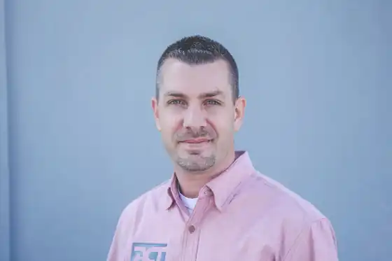 Jared Holwegner, general manager at ACT Heat & Air, in front of a blue wall