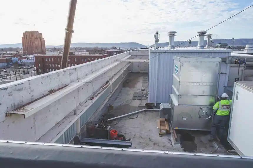 A rooftop cooling tower with the ACT crew small in the frame
